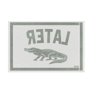May include: A rectangular, off-white sign with a gray border and text. The word "LATER" is printed in large, gray, reversed letters above a gray alligator illustration. The design has a vintage, screen-printed aesthetic.