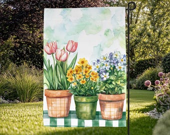 May include: A garden flag with watercolour illustrations of potted flowers. The flag shows pink tulips, yellow daisies, and purple and white flowers in terracotta and green pots. The background has a green and blue watercolour wash.