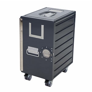 May include: A dark gray rolling storage cart with a rectangular shape. It features a handle on top, a side handle, and a circular access point. The cart has multiple horizontal lines on the side and is mounted on four small wheels.