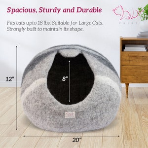 May include: Gray and white cat bed with a black interior. The bed is 20 inches wide, 12 inches tall, and 8 inches deep. The bed is made of a soft, fuzzy material.