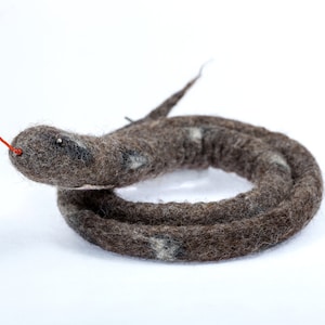 May include: A brown and white felted snake toy with a red tongue. The snake is curled up in a circle.