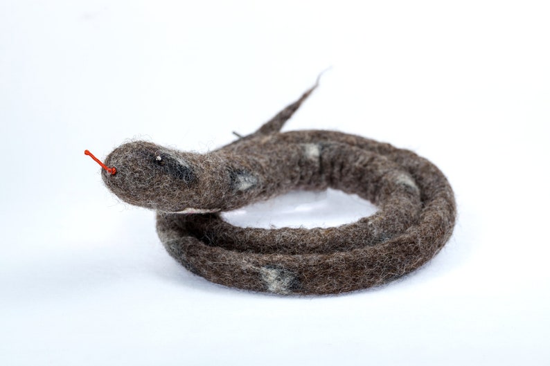 May include: A brown and white felted snake toy with a red tongue. The snake is curled up in a circle.