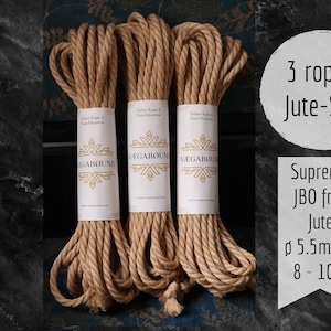 Könnte beinhalten: Drei Bündel aus naturfarbenem Juteseil, jeweils mit einer weißen Papierbanderole mit der Aufschrift VÆGABØUND versehen. Der Text lautet 3 ropes Jute-Set, Supreme JBO free Jute und ø 5,5 mm / 8 - 10 m. Die Seile haben eine gedrehte Struktur.