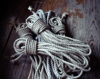 May include: A bundle of thick, natural-coloured twisted fibre rope coiled into several loops. The rope features a textured, multi-strand construction with visible knots securing the ends of each individual coil within the larger bundle.