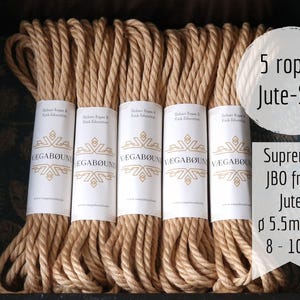 Könnte beinhalten: Ein Set aus fünf beigefarbenen Juteseilen, die jeweils mit einer weißen Papierbanderole mit der Aufschrift VÆGABØUND versehen sind. Der Text lautet 5 ropes Jute-Set, Supreme JBO free Jute, mit 5,5 mm Durchmesser und 8 bis 10 Metern Länge.