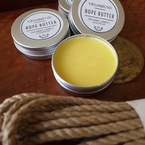 a collection of rope butter jars on a wooden surface, with a rope coiled nearby.