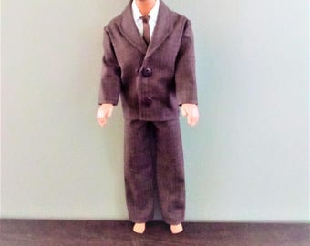 May include: A brown pinstripe suit with a white collared shirt and a dark tie. The suit has a double-breasted jacket with four buttons.