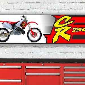 May include: A red, white, and black banner with a yellow and black "CR 250R" logo. A white Honda dirt bike is featured on the left side of the banner.