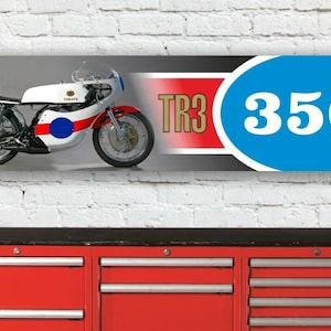 Könnte beinhalten: Ein weißes Yamaha TR3 350 Motorrad mit blauen und roten Akzenten. Das Motorrad befindet sich auf einem Banner mit dem Text "TR3 350" in einem blauen Kreis.