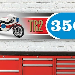 Könnte beinhalten: Ein Vintage-Banner mit einer Yamaha TR2 350-Motorrad mit rotem, schwarzem und weißem Hintergrund. Das Motorrad ist weiß mit blauen und roten Akzenten. Das Banner hat einen blauen Kreis mit der Nummer 350 in weiß.
