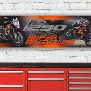 Puede incluir: Una pancarta con fondo naranja y negro que muestra dos motocicletas. El texto "1290 SUPER ADVENTURE" se muestra en letras grandes, negritas y grises.