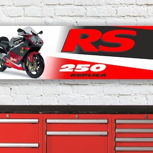 Pode incluir: Uma faixa vermelha, branca e preta com uma imagem de uma motocicleta e o texto "RS 250 REPLICA".