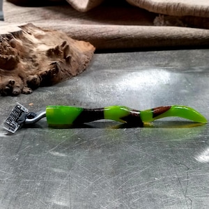 May include: A green and brown safety razor with a curved handle. The handle has a camouflage pattern.