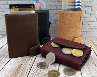 May include: A collection of four wallets in brown, black, cork, and burgundy leather. The wallets feature card slots, metal coin compartments, and the text G-WALLET embossed on the side. Several gold and silver coins are scattered in the foreground.