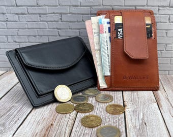 Op de afbeelding: Een zwarte leren portemonnee met klepsluiting en een bruine leren portemonnee met het opschrift G-WALLET en een verticale band, beide gevuld met papiergeld en kaarten, met verspreide gouden en zilveren munten op een houten ondergrond.