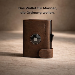 Op de afbeelding: Bruin leren portemonnee met een zwart schuifmechanisme en een zilveren Apple AirTag. De portemonnee heeft de tekst "G-Wallet" in reliëf. De tekst bovenaan luidt "Das Wallet für Männer, die Ordnung wollen."
