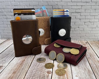 May include: Four wallets in brown, cork, black, and burgundy leather. The brown, cork, and black wallets feature a circular cutout for an AirTag and hold cards and cash. The burgundy wallet is folded with several gold and silver coins scattered.