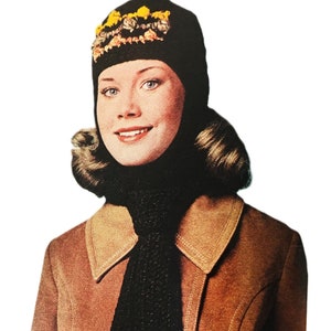 May include: A black crocheted hat and scarf set with yellow and pink floral accents. The hat has a pointed crown and the scarf has two decorative crocheted squares.
