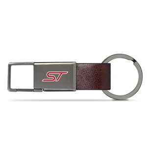 May include: A rectangular metal keychain featuring a dark gunmetal finish and a textured brown leather strap. The center of the metal plate displays the letters ST in red with a white outline. A circular metal split ring is attached to the end.