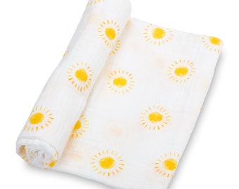May include: White baby blanket featuring a pattern of yellow suns. The blanket is rolled up, revealing the soft, lightweight fabric. The suns have a watercolor effect. The blanket is suitable for a baby.