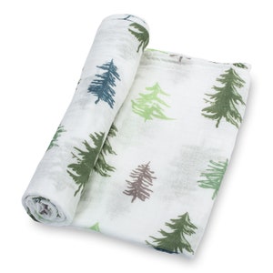 May include: A white muslin swaddle blanket with a green, brown, and blue pine tree pattern. The blanket is rolled up and partially unrolled, showing the pattern.