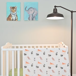 Swaddle with a cute cat print draped over a crib in a nursery, adding a touch of whimsy.