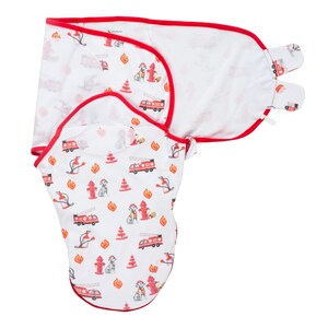 May include: White baby swaddle blanket with a red trim and a pattern of red fire trucks, fire hydrants, flames, and Dalmatian-like dogs. The blanket is designed to wrap around a baby.