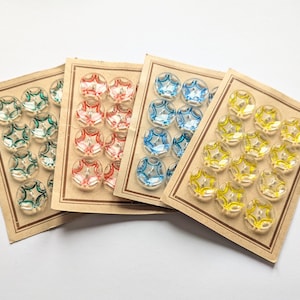 May include: Four vintage button cards with clear, star-shaped buttons in green, red, blue, and yellow. Each card has a brown border and contains multiple buttons, perfect for sewing or craft projects.