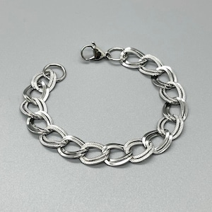 May include: A silver chain bracelet with a lobster clasp closure. The chain is made of oval links with a textured design.