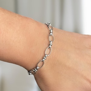 May include: A silver chain bracelet with oval links and small round beads.