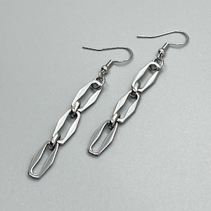 May include: A pair of silver chain earrings with a long, rectangular link design.