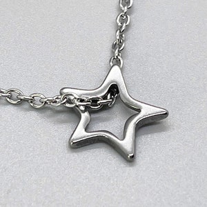 May include: A silver chain necklace with a star-shaped pendant. The star is hollow and has a delicate design.