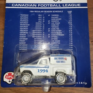 May include: A white Matchbox 1994 Limited Edition Baltimore CFLs toy truck with a blue stripe and "Baltimore Football" printed on the side. The truck is on a blue background with a 1994 CFL regular season schedule printed on the back.