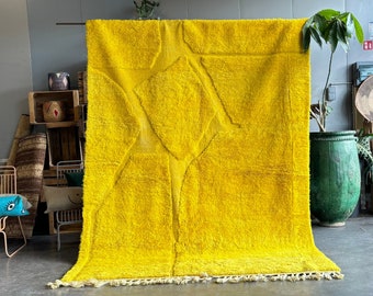 May include: A large, bright yellow rug with a geometric pattern. The rug has a fringe border and is made of a soft, fluffy material.