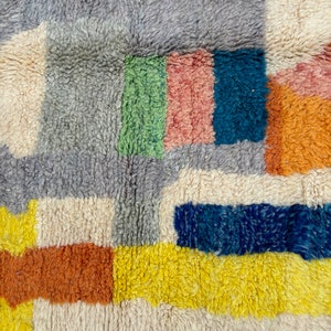 May include: A colorful, geometric rug with a variety of textures. The rug features squares and rectangles in shades of blue, red, yellow, green, orange, and white.