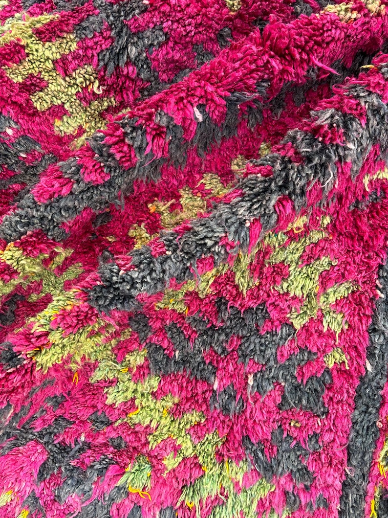 May include: A close-up of a plush, textured rug with a vibrant color palette. The rug features a pattern of magenta, gray, and lime green. The thick pile creates a soft, inviting appearance, suitable for a living room or bedroom.