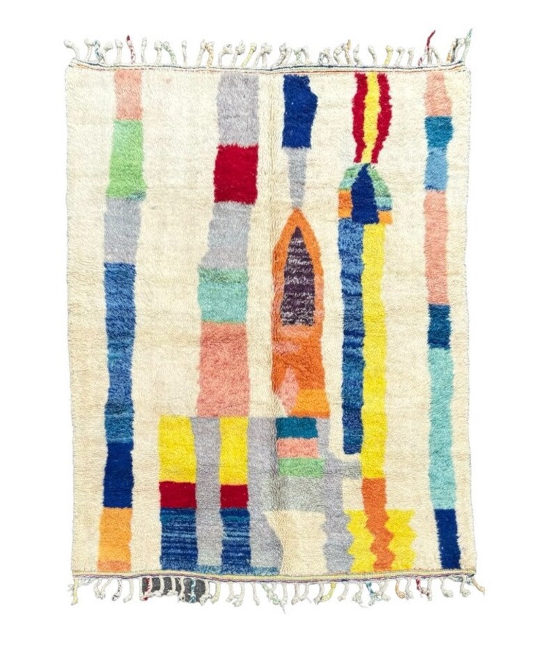 May include: A colorful Moroccan rug with a geometric design featuring a variety of colors including red, blue, yellow, green, and orange. The rug has a white background and a fringe border.