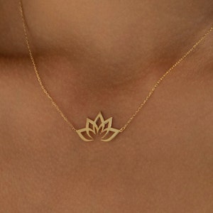 May include: A gold chain necklace with a delicate lotus flower pendant. The pendant is made of a single piece of metal and has a cutout design.