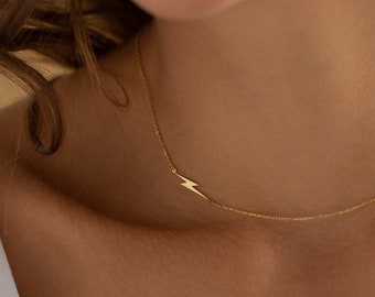 May include: A gold necklace with a lightning bolt pendant. The necklace is delicate and simple, making it a perfect everyday piece of jewelry.