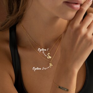 May include: Two gold-colored snake pendant necklaces. Option 1 features a stylized snake, while Option 2 presents a more minimalist snake design. The image also shows a gold bracelet with a dark stone.