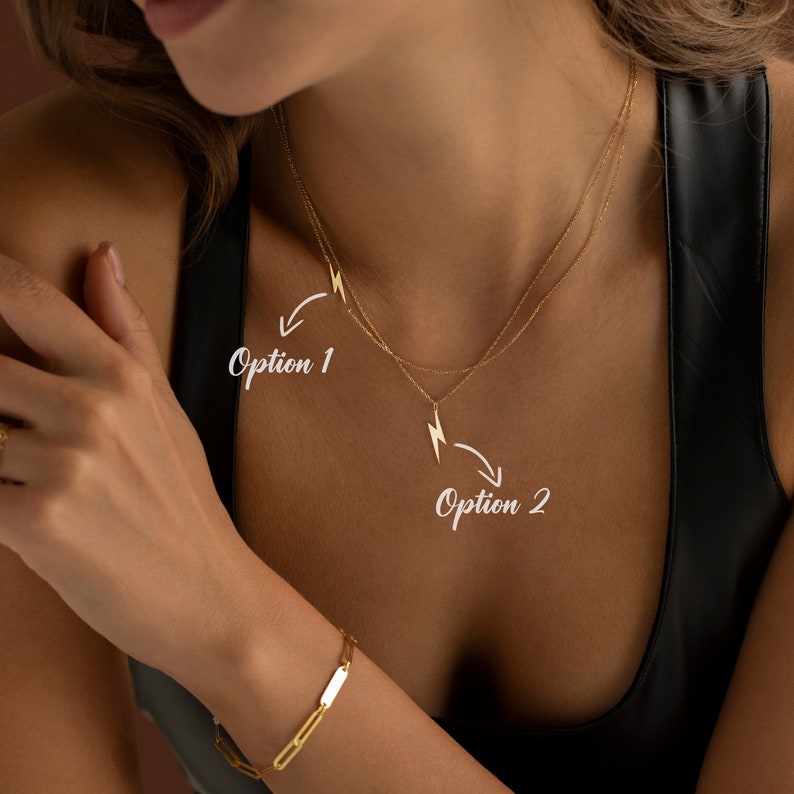 May include: Two gold necklaces with lightning bolt pendants. The top necklace has a smaller pendant and the bottom necklace has a larger pendant. The text "Option 1" and "Option 2" are written on the image.
