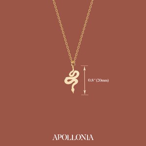 May include: A gold-colored snake pendant necklace. The snake pendant is 0.8 inches (20mm) long and hangs from a delicate chain. The word "APOLLONIA" is printed at the bottom of the image.