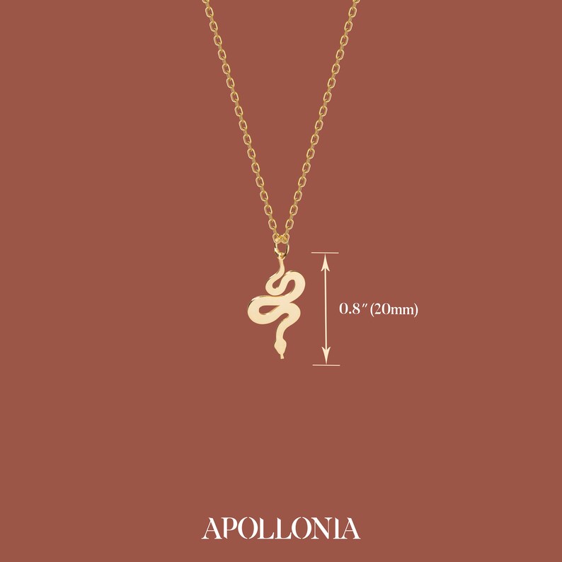 May include: A gold-colored snake pendant necklace. The snake pendant is 0.8 inches (20mm) long and hangs from a delicate chain. The word "APOLLONIA" is printed at the bottom of the image.