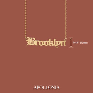 May include: Gold necklace with a nameplate pendant that reads "Brooklyn" in a gothic font. The pendant is 0.48 inches (12 mm) tall.