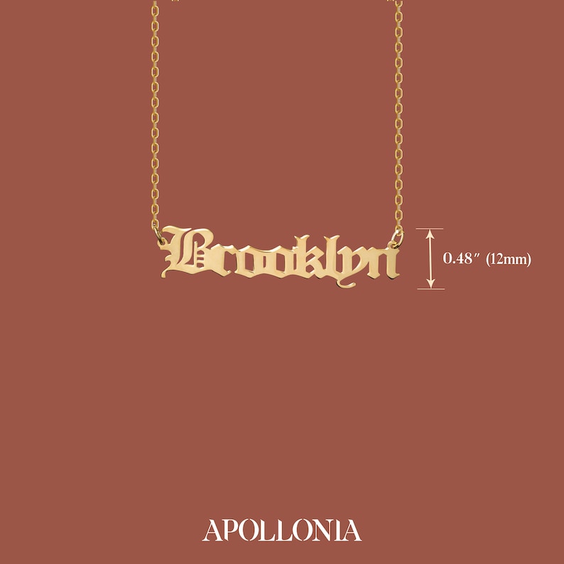May include: Gold necklace with a nameplate pendant that reads "Brooklyn" in a gothic font. The pendant is 0.48 inches (12 mm) tall.