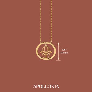 Puede incluir: Collar de oro con un dije de mano de hamsa con un ojo en el centro. El dije tiene un di&aacute;metro de 20 mm.
