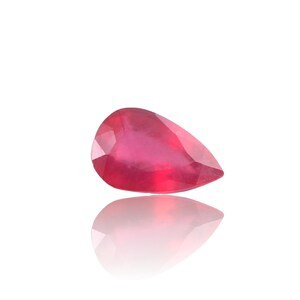 May include: A pear-shaped ruby gemstone with a deep red color. The gemstone is faceted and has a high polish.