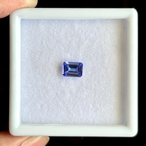 May include: A blue gemstone with a rectangular shape, set in a white box.