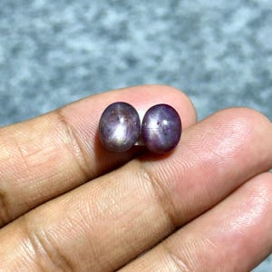 以下が含まれることがあります： 2つの楕円形の紫色のスターサファイア。それぞれの中心に6つのポイントを持つ星があります。