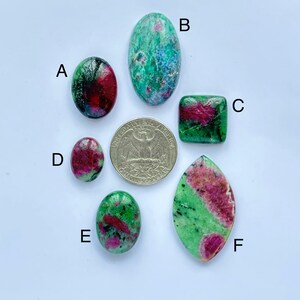 Peut inclure: Six cabochons de pierres précieuses vertes et roses de tailles et de formes différentes. Les cabochons sont disposés en cercle autour d'un quart de dollar américain.